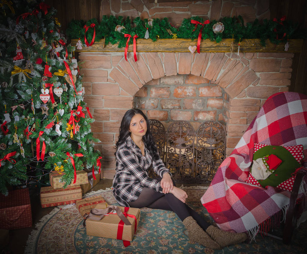Christmas beautiful girl sitting near the fireplace - Foto, imagen
