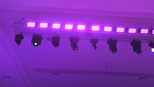 Equipo de iluminación de concierto en el trabajo. Proyectores de iluminación profesionales giraban automáticamente y brillaban de diferentes colores. Los rayos del equipo de luz entran en la lente de la cámara
. - Metraje, vídeo