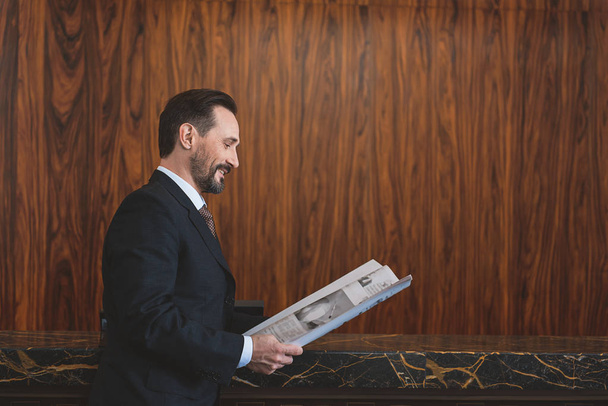Man in suit holding journal near reception desk - Foto, Bild