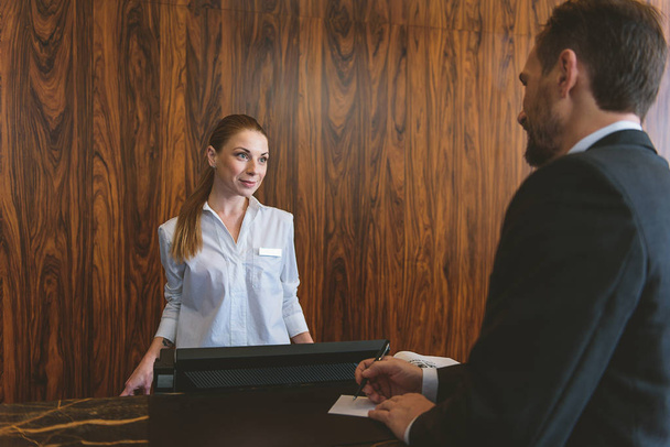 Receptionist looking at man in suit - Foto, afbeelding