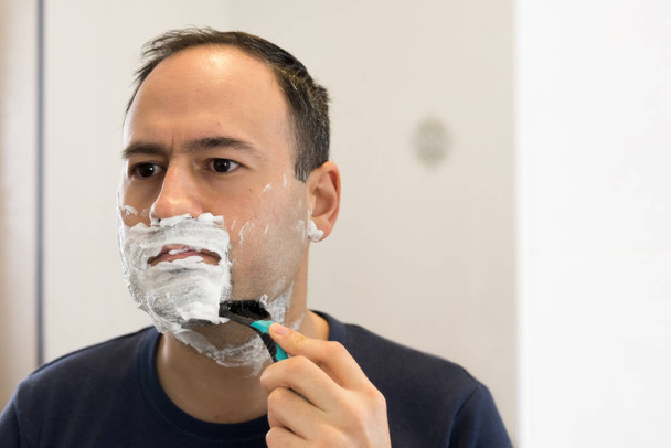 Adam banyoda jilet mirron köpük tıraş - Fotoğraf, Görsel