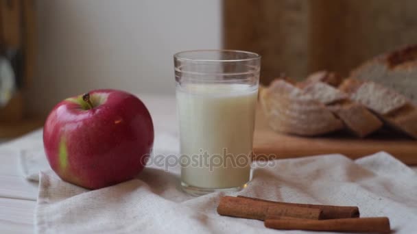 Πρωινό το πρωί. Σύνθεση των τροφίμων στο τραπέζι. Κόκκινο μήλο και ποτήρι γάλα. - Πλάνα, βίντεο