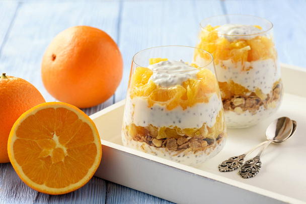 Yogurt dessert with muesli, chia seeds and oranges. - Фото, изображение
