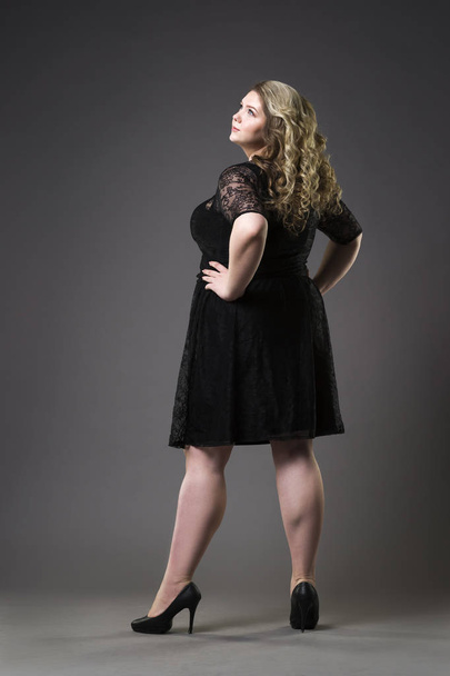 Young beautiful plus size model in black dres, xxl woman on gray studio background - Фото, изображение