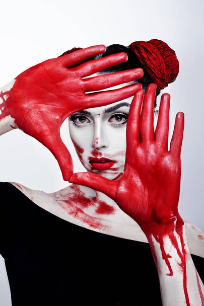 Portrait of a girl in a high fashion, beauty style with  red palms facing behalf, white skin, red lips make up at silver background. Vampire makeup Fashion Art design. Halloween holiday concept - Foto, Bild