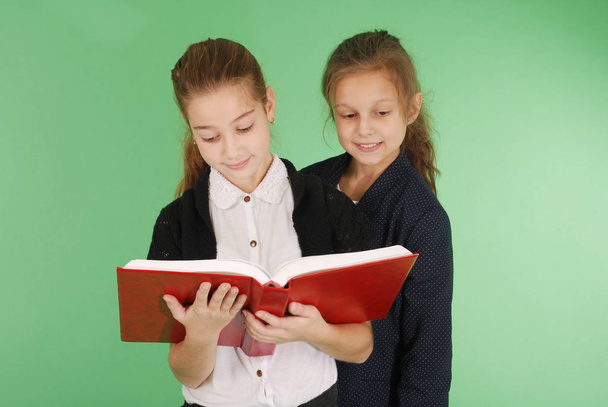 Kaksi nuorta koulutyttöä punaisella kirjalla
 - Valokuva, kuva