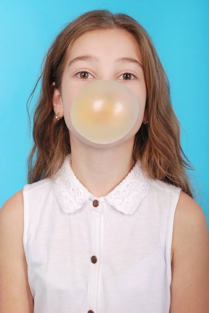 Chica joven haciendo una gran burbuja con un chicle
 - Foto, imagen