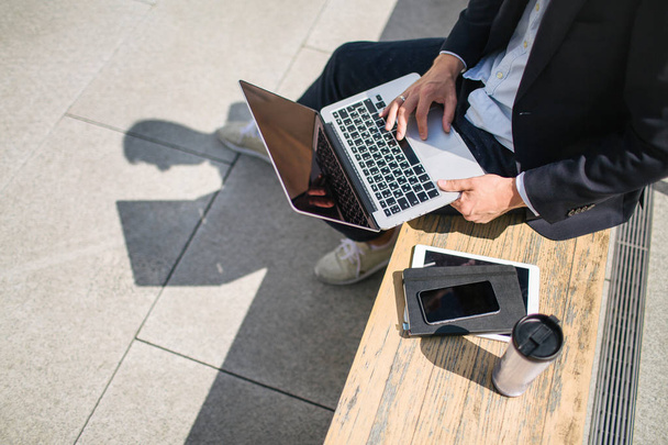 Jovem homem de negócios hipster em terno digitando laptop perto de escritório outd
 - Foto, Imagem