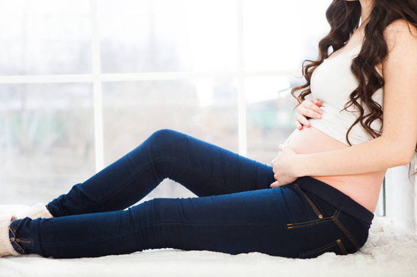 Νέοι ευτυχισμένη έγκυος γυναίκα κάθεται στο παράθυρο της σπίτι, cl - Φωτογραφία, εικόνα