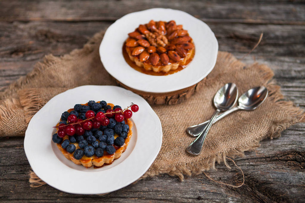 Almonds tart and Walnut tartlets with custard and berries on woo - Zdjęcie, obraz