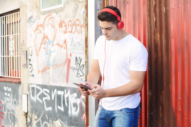 Latin man using a tablet with headphones - Foto, Imagen
