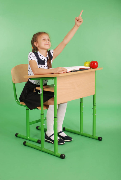 Chica en un uniforme escolar levantando la mano para hacer una pregunta
 - Foto, Imagen