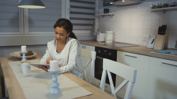 A beautiful young African American woman using a tablet computer in a kitchen. - Video