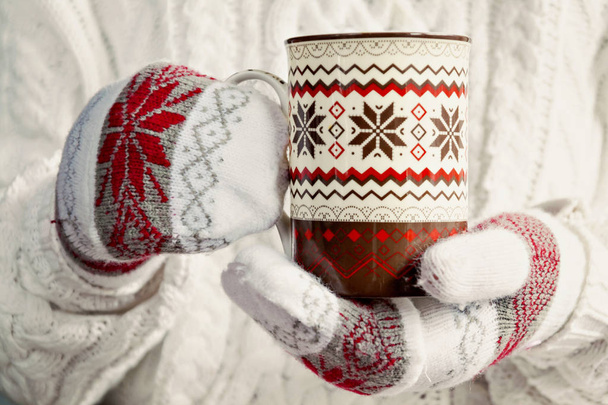 mains dans les mitaines tenant une tasse de motif scandinave de Noël
 - Photo, image