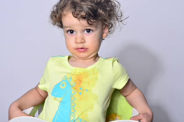 Beautiful curly toddler looking surprised, boy being upset because he got dirty while eating - Foto, immagini