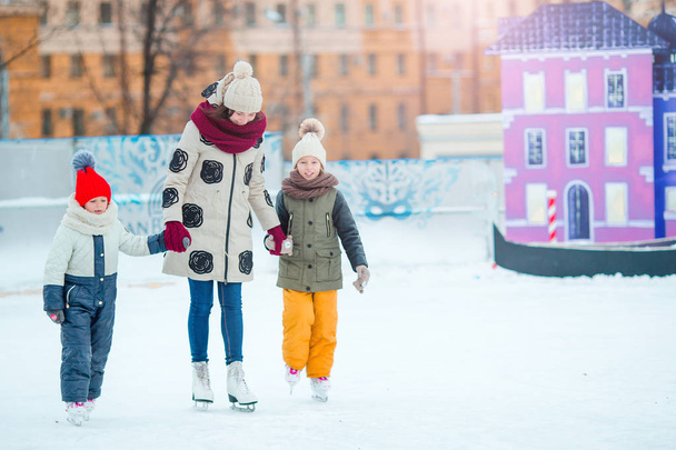 Kleine schattige meisjes met moeder leren schaatsen op de ijsbaan - Foto, afbeelding