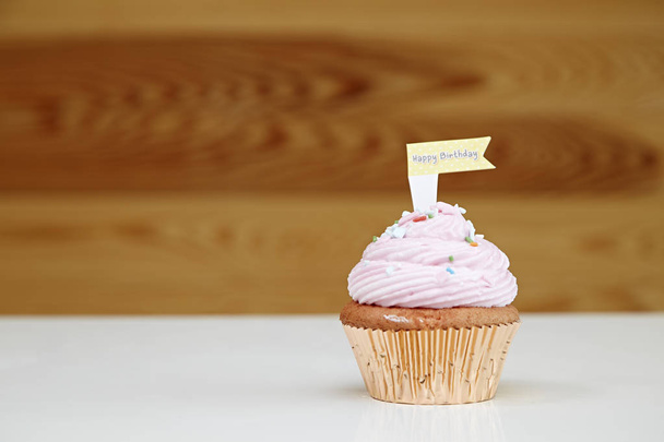 Pink happy birthday cupcake on table on light background - Foto, afbeelding