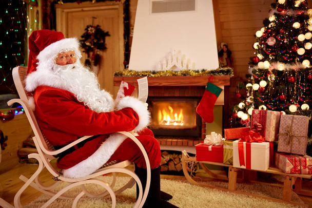 Santa Claus enjoying and reading children wishes for x-mas - Foto, afbeelding