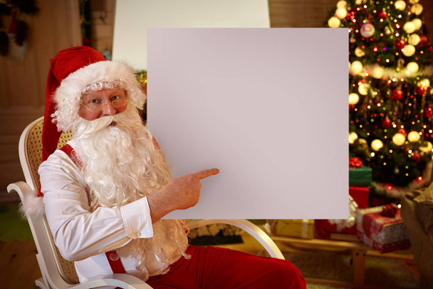 Smiling Santa Claus pointing in empty banner - Foto, imagen