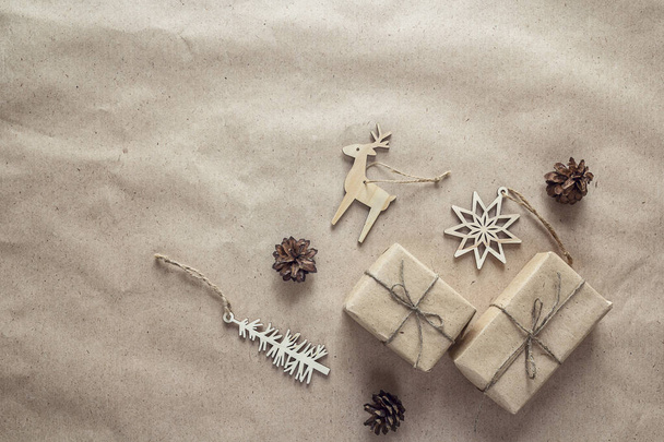 Christmas gifts, wooden decorations and cones on brown wrapping  - Fotoğraf, Görsel