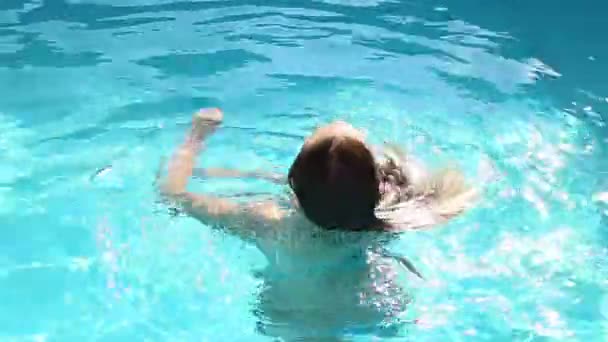 young happy woman swimming and whirls in a swimming pool - Video, Çekim