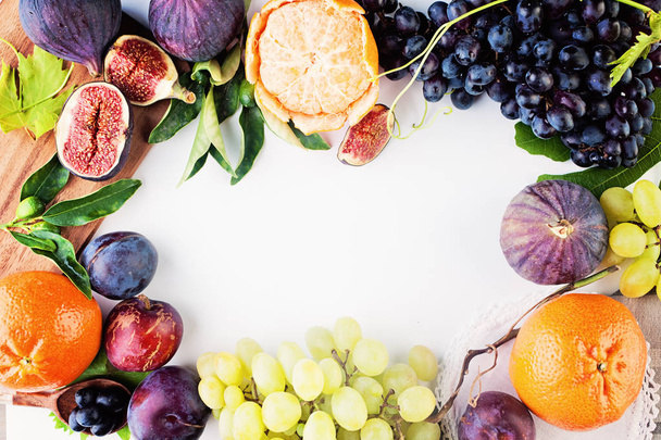 Fruit achtergrond met druivenmost, Plum, mandarijnen, vijgen op witte Pap - Foto, afbeelding
