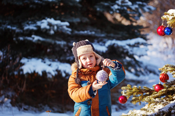 Portrait of a boy with christmas ball walking in the winter nature. Playing with snow. Concept happy childhood - Photo, Image