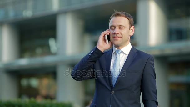 Atrakcyjny biznesmen rozmawia przez telefon, w mieście - Materiał filmowy, wideo