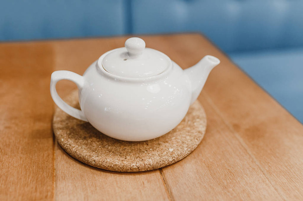Bir tabloda bir kafede bir stand beyaz güzel çaydanlık - Fotoğraf, Görsel