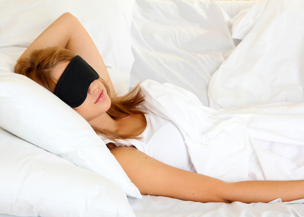 Junge schöne Frau schläft im Bett mit Augenmaske - Foto, Bild