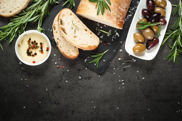 Pão ciabatta italiano em ardósia preta com ervas e azeitonas
. - Foto, Imagem