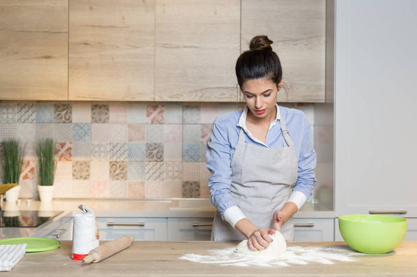 Young woman knead dough at kitchen - 写真・画像