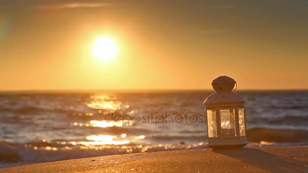 Valkoinen lyhty rannalla auringonlaskun aikaan
 - Materiaali, video