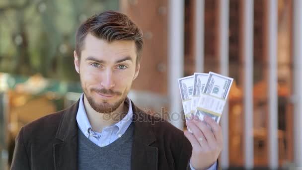 Happy attractive man holding in his hand bundles of money cash dollars - Imágenes, Vídeo