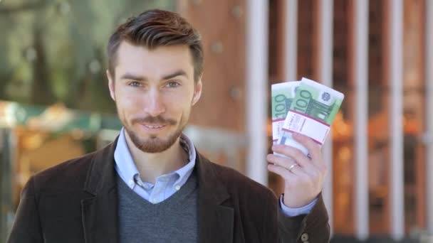 Szczęśliwy człowiek atrakcyjny gospodarstwa w jego dłoni wiązki pieniędzy Gotówka Euro - Materiał filmowy, wideo