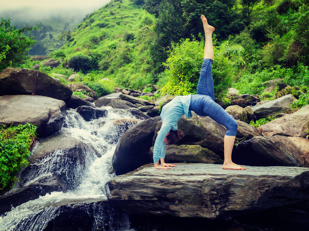 vrouw doet yoga asana bij waterval - Foto, afbeelding
