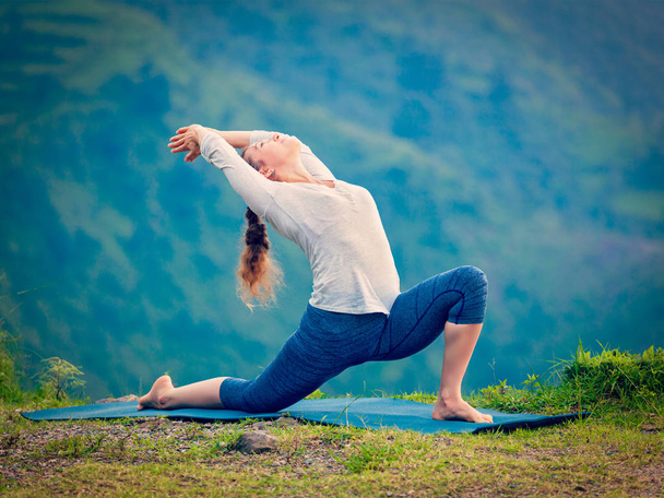 Donna in forma sportiva pratica yoga asana Anjaneyasana in montagna - Foto, immagini
