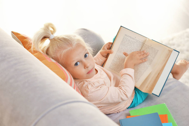 Small girl reading book on couch - Foto, Imagem