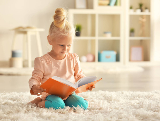 Small girl reading book on carpet - Foto, Bild