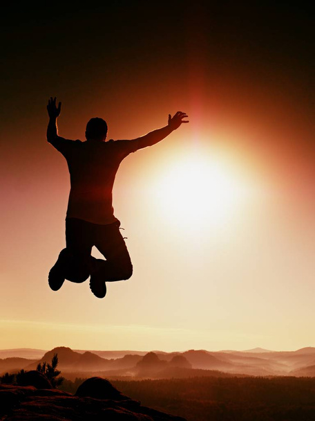Skaczący Człowiek. Młody człowiek szalony skacze na tle czerwonego nieba. Sylwetka skoki człowieka - Zdjęcie, obraz