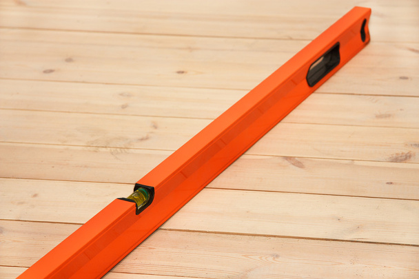 Orange building spirit level on a wooden floor - Φωτογραφία, εικόνα