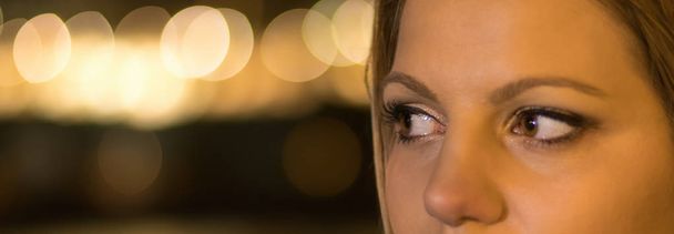 Close up of a brown woman eyes night lights bokeh. - Foto, Bild