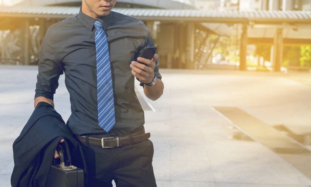 Businessman using mobile phone with city background - Zdjęcie, obraz