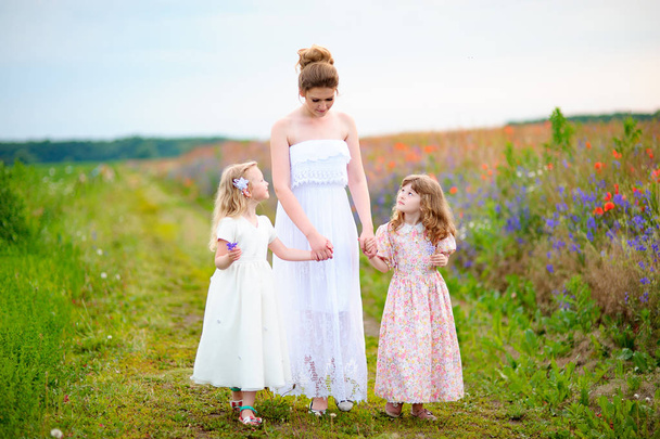 Happy woman and her little daughters in the field. Mother day or - Photo, Image