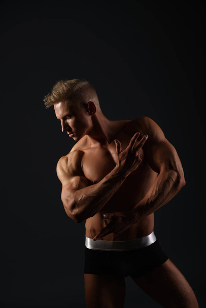 Sexy bodybuilder in briefs posing in his profile - 写真・画像