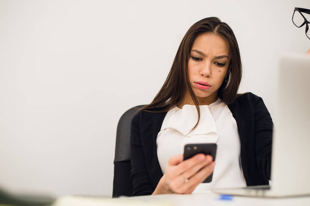 Femme ennuyée à son bureau dactylographier message sur téléphone mobile
 - Photo, image