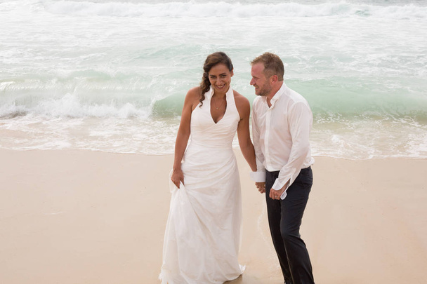 mooie paar huwelijk wandelen op het strand bruiloft plaats - Foto, afbeelding