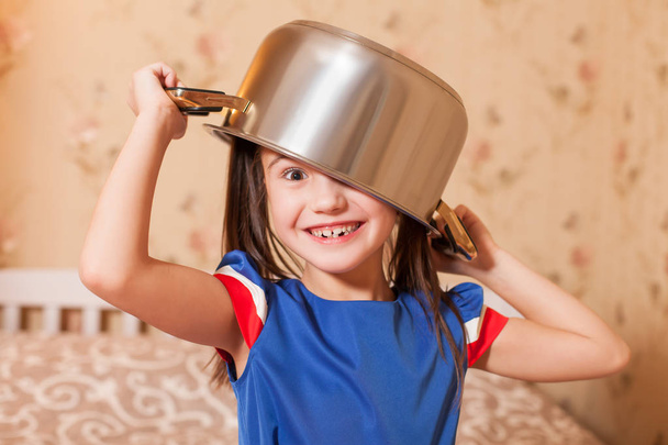 girl fooling around with pan on head - Foto, afbeelding