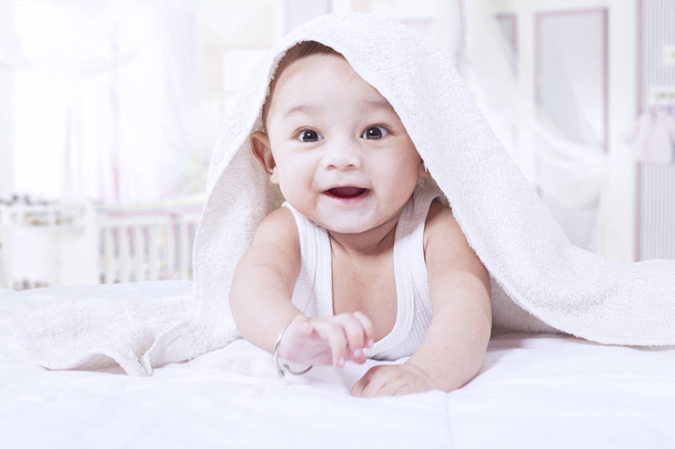 Cheerful baby boy under towel - Foto, afbeelding