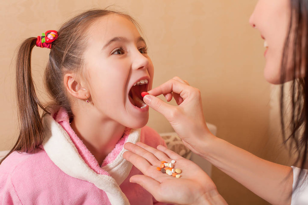 umieszczenie tabletki w usta dziewczyny, matka - Zdjęcie, obraz